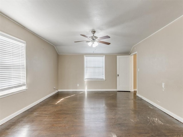 spare room featuring lofted ceiling, dark hardwood / wood-style flooring, ceiling fan, and a healthy amount of sunlight