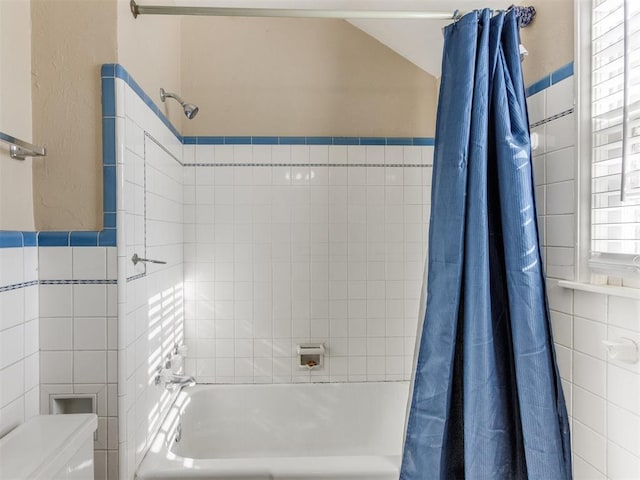 bathroom with shower / bath combination with curtain, tile walls, and toilet