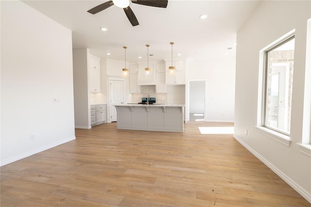 unfurnished living room featuring ceiling fan, sink, and light hardwood / wood-style floors