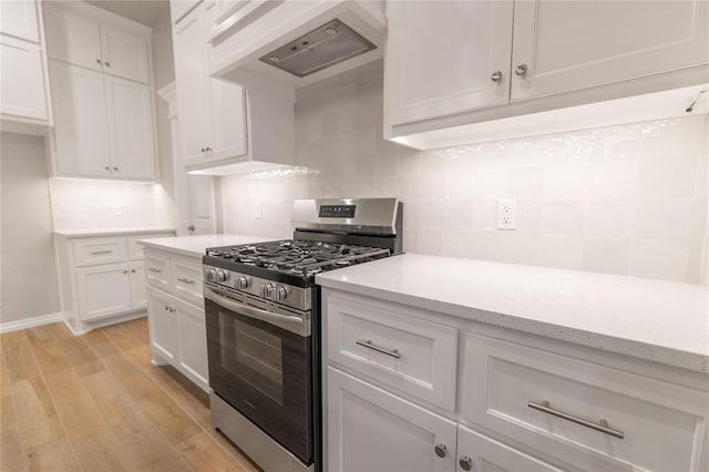 kitchen featuring tasteful backsplash, stainless steel range with gas cooktop, white cabinets, and light wood-type flooring