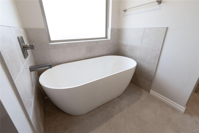 bathroom featuring a tub to relax in, tile patterned flooring, and tile walls