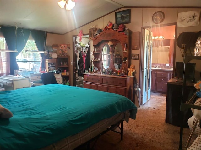 carpeted bedroom with a closet, sink, connected bathroom, and vaulted ceiling