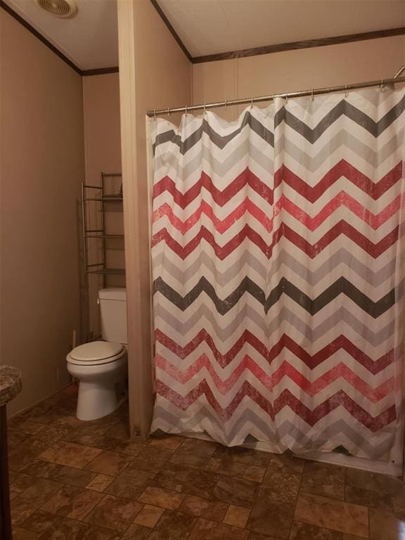 bathroom with toilet, ornamental molding, and walk in shower