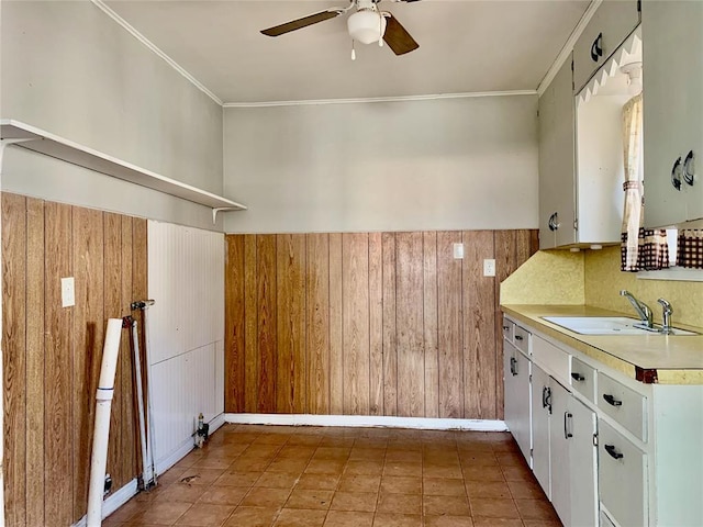 kitchen featuring wood walls, white cabinetry, sink, and tasteful backsplash