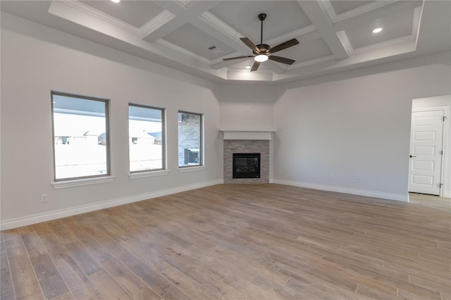 unfurnished living room featuring coffered ceiling, ceiling fan, light hardwood / wood-style floors, and a stone fireplace