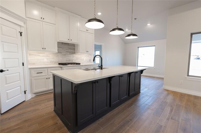 kitchen featuring decorative light fixtures, white cabinetry, vaulted ceiling, dark hardwood / wood-style floors, and a kitchen island with sink