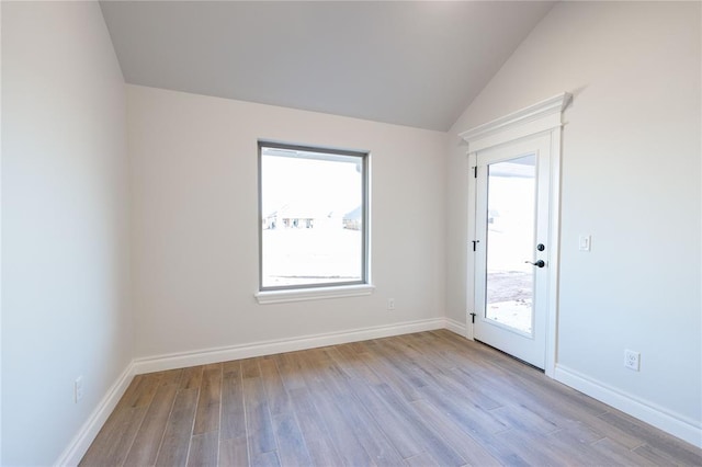 empty room with lofted ceiling, light hardwood / wood-style floors, and a healthy amount of sunlight