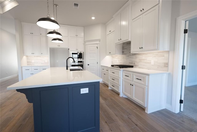 kitchen featuring an island with sink, appliances with stainless steel finishes, white cabinets, and sink