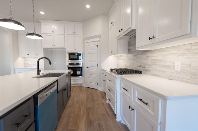 kitchen featuring stainless steel appliances, an island with sink, pendant lighting, white cabinets, and sink