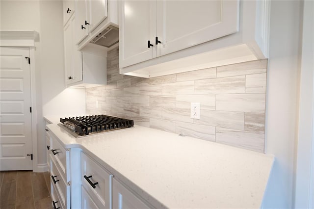 kitchen featuring white cabinets, dark hardwood / wood-style flooring, backsplash, and stainless steel gas cooktop