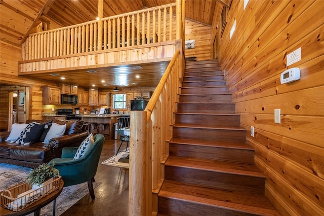 stairs featuring wooden walls, wooden ceiling, and high vaulted ceiling