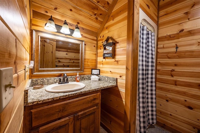 bathroom featuring lofted ceiling, vanity, and wooden walls