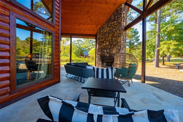 sunroom with an outdoor stone fireplace, vaulted ceiling, and wood ceiling