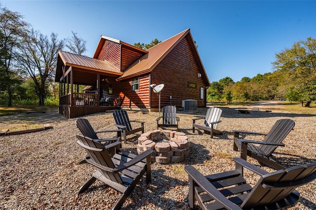 rear view of property with a fire pit and central AC unit