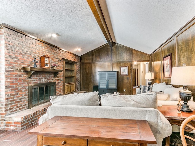 living room featuring a textured ceiling, wood walls, light wood-type flooring, and a fireplace