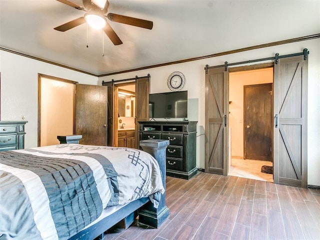 bedroom with hardwood / wood-style floors, ensuite bathroom, ceiling fan, a barn door, and ornamental molding