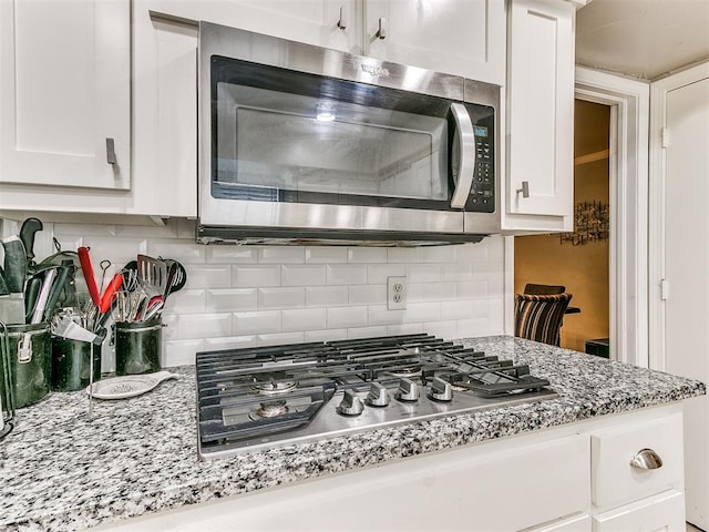 kitchen with white cabinets, appliances with stainless steel finishes, and decorative backsplash