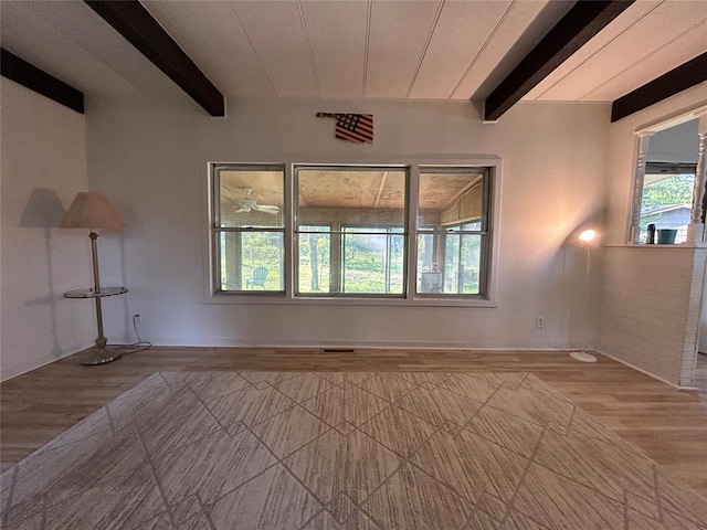 unfurnished room featuring beam ceiling and light wood-type flooring