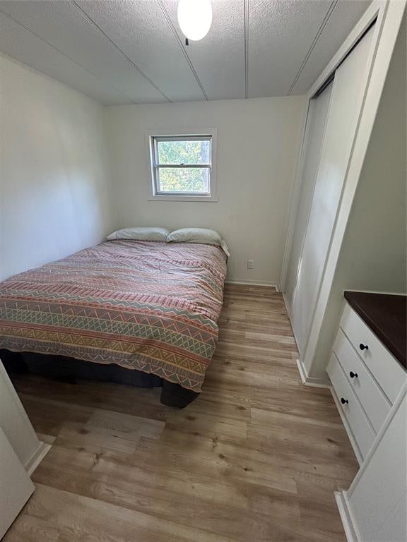 bedroom with a textured ceiling, light hardwood / wood-style flooring, and a closet