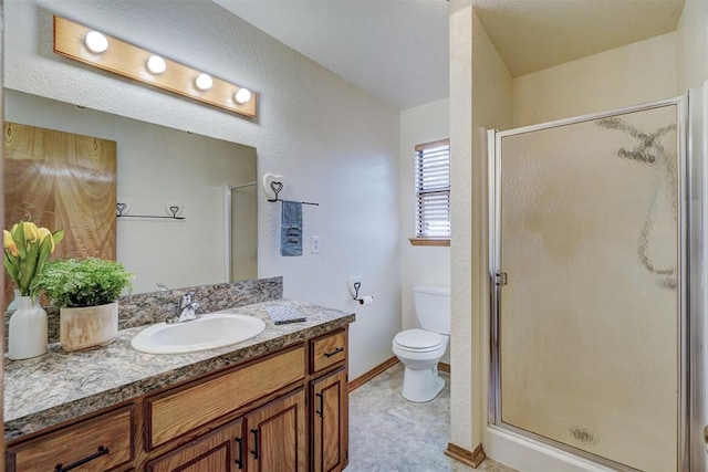 bathroom with a shower with door, vanity, and toilet