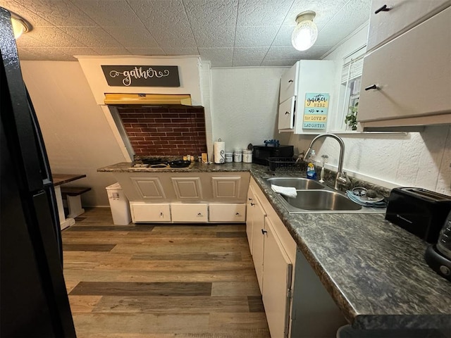 kitchen featuring white cabinets, dark hardwood / wood-style flooring, dark stone counters, and sink