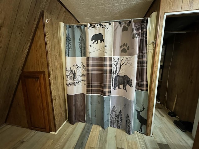 bathroom featuring hardwood / wood-style flooring, curtained shower, and wooden walls