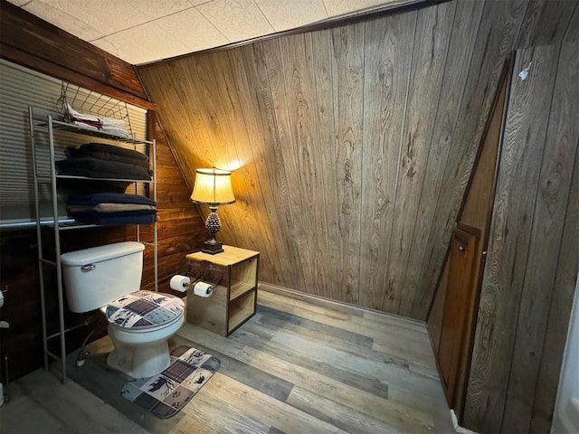 bathroom featuring wood walls, toilet, lofted ceiling, and hardwood / wood-style flooring