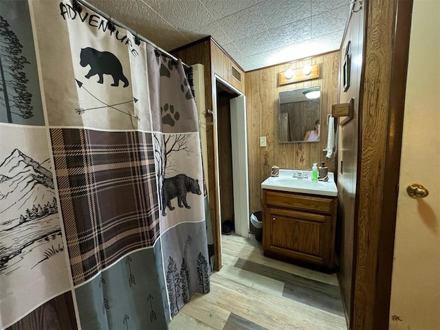 bathroom featuring wood-type flooring, vanity, a shower with curtain, and wooden walls