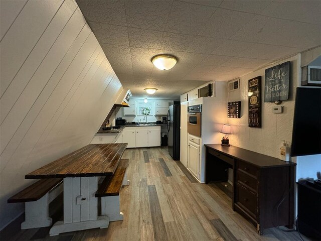 kitchen featuring black appliances, butcher block countertops, white cabinets, and light hardwood / wood-style flooring