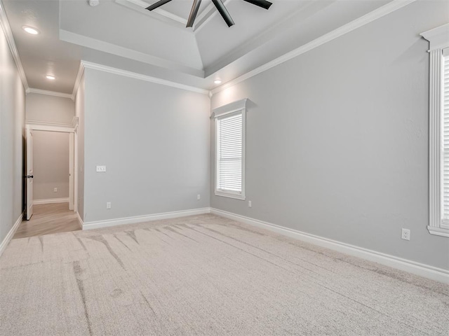 carpeted empty room featuring a tray ceiling, ornamental molding, and ceiling fan