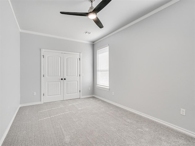 unfurnished bedroom with ornamental molding, light colored carpet, ceiling fan, and a closet