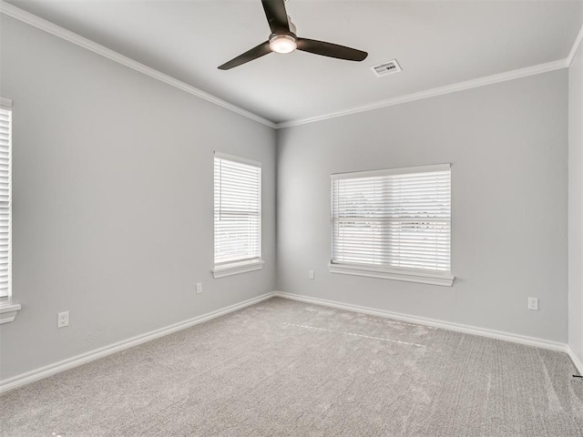 carpeted spare room with a wealth of natural light, ornamental molding, and ceiling fan