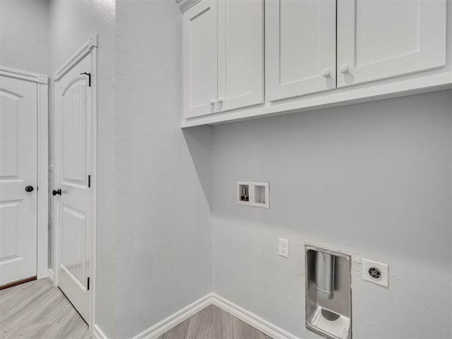 clothes washing area with electric dryer hookup, hookup for a washing machine, light hardwood / wood-style floors, and cabinets