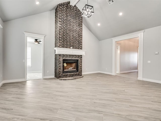 unfurnished living room with high vaulted ceiling, light wood-type flooring, and a fireplace