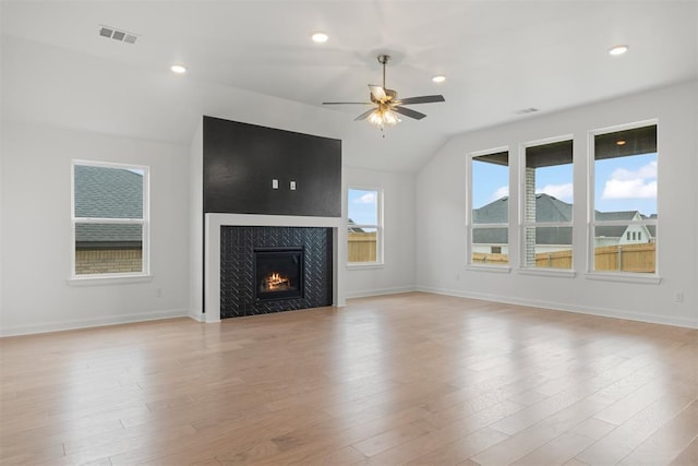 unfurnished living room featuring ceiling fan, vaulted ceiling, a fireplace, and light hardwood / wood-style flooring