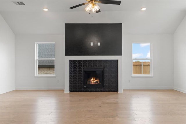 unfurnished living room featuring ceiling fan, light hardwood / wood-style floors, lofted ceiling, and a fireplace