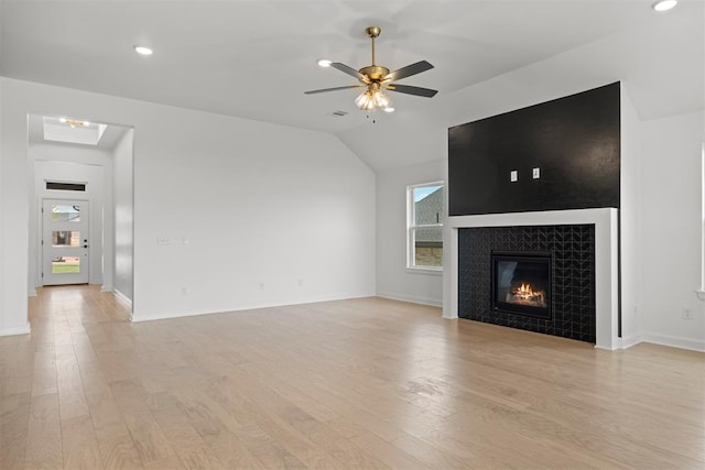 unfurnished living room featuring ceiling fan, a fireplace, lofted ceiling, and light wood-type flooring