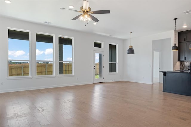 unfurnished living room featuring light hardwood / wood-style floors, ceiling fan, and a healthy amount of sunlight