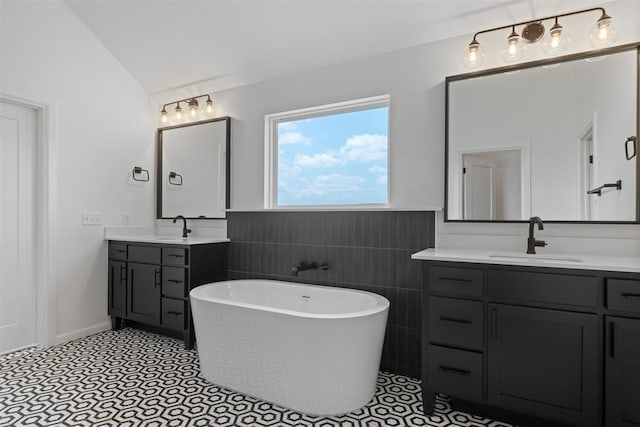 bathroom featuring vanity, tile patterned floors, vaulted ceiling, tile walls, and a tub