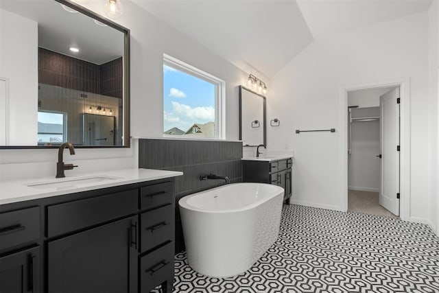 bathroom with tile patterned flooring, vanity, a bathtub, and lofted ceiling