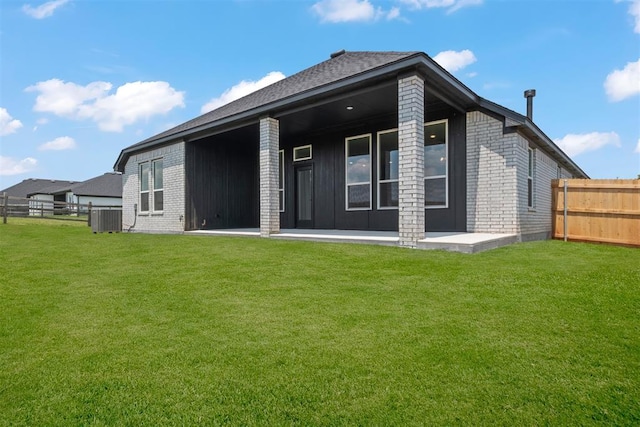 rear view of property featuring a lawn and central AC