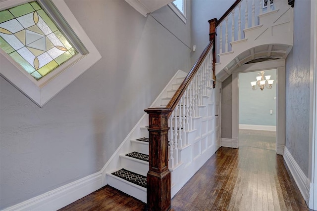 staircase featuring hardwood / wood-style flooring, a healthy amount of sunlight, and a chandelier