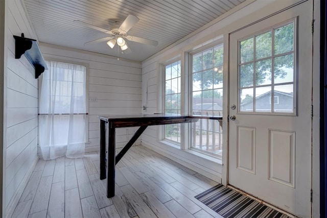 entryway with ceiling fan, wooden walls, wood ceiling, and light wood-type flooring