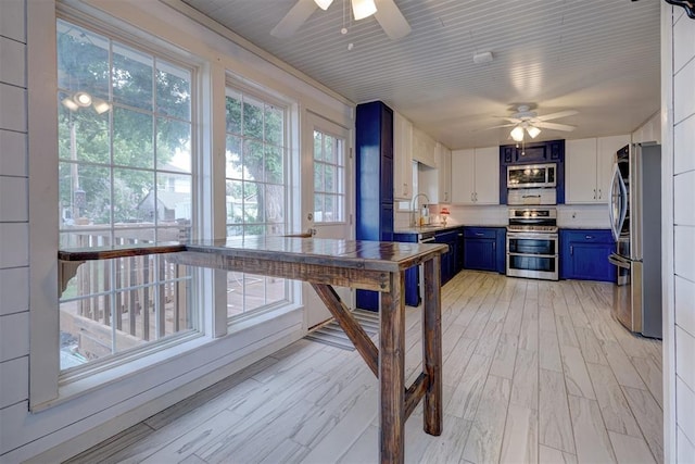 kitchen with ceiling fan, white cabinetry, blue cabinets, and stainless steel appliances