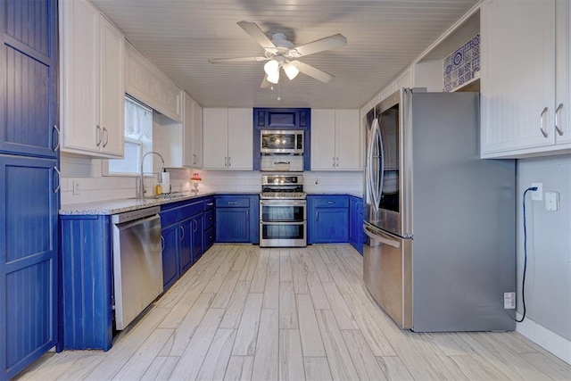 kitchen featuring stainless steel appliances, blue cabinets, ceiling fan, sink, and white cabinets