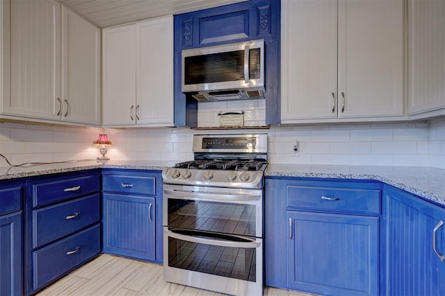 kitchen featuring white cabinets, light stone counters, blue cabinets, and appliances with stainless steel finishes