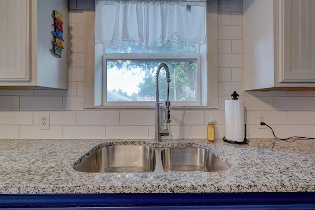 interior details with light stone countertops, backsplash, and sink