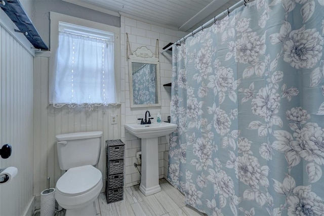 bathroom featuring a shower with shower curtain, toilet, and sink