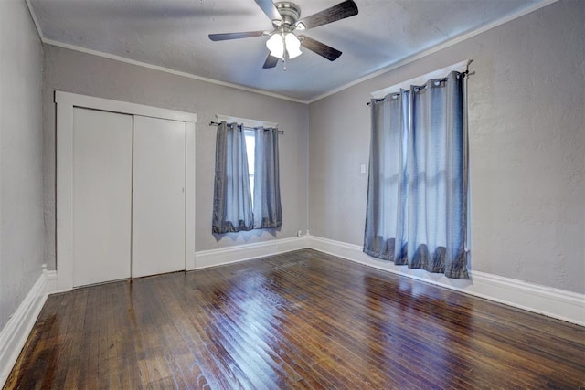 unfurnished bedroom with ceiling fan, dark hardwood / wood-style floors, ornamental molding, and a closet