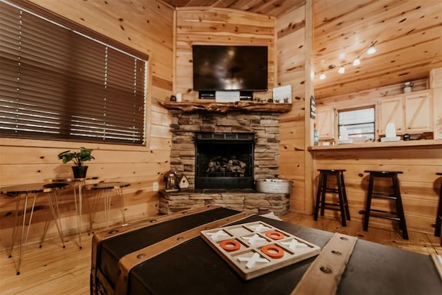 living room featuring a fireplace, light wood-type flooring, and wood walls